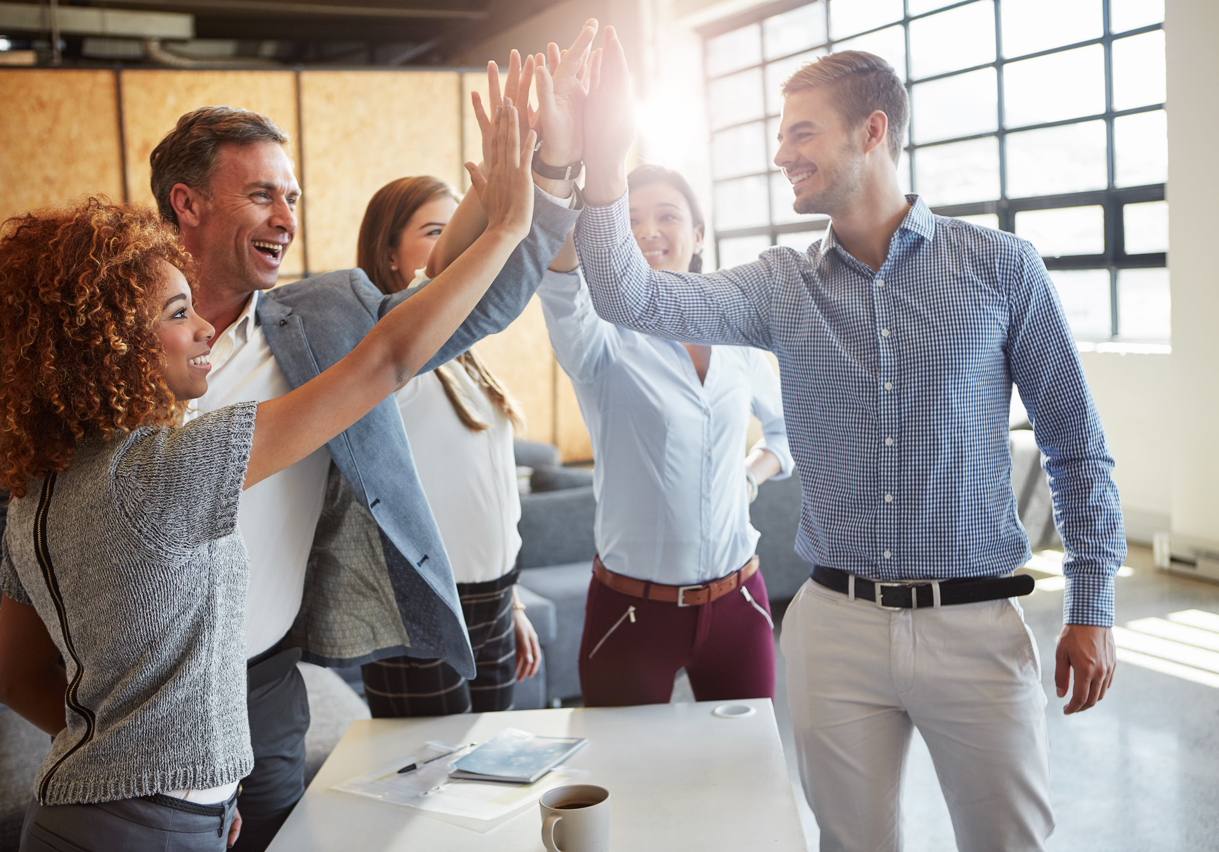 Cropped shot of a group of businesspeople high fiving in the office